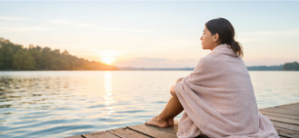 woman sitting by a lake at sunset wellness self-care moment